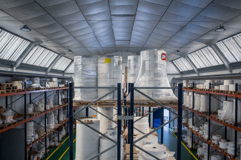 Estanterías del almacén con bobinas de material para fabricar etiquetas